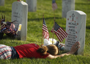A mourner, believed to be Air Force Reserve Captain Teresa Dutcher lays at the grave of Corporal Michael Avery Pursel at Arlington National Cemetary in Arlington, Virginia. She visits the cematery at the conclusion of the "Flags In" on May 24, 2012. Each year for the past 40 years, the 3rd U.S. Infantry or "Old Guard" honors America's war dead by placing American flags at the gravestones of service members buried at Arlington National Cemetery prior to Memorial Day weekend. The tradition, known as "flags in," is conducted annually by the 3rd U.S. Infantry, the Army's official ceremonial unit. Every available soldier in the 3rd U.S. Infantry participates, placing a small American flag one foot in front and centered before each grave marker over a three-hour period. During this time, the soldiers place flags in front of more than 260,000 gravestones.